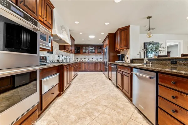 a large kitchen with stainless steel appliances kitchen island granite countertop a stove a sink and a microwave