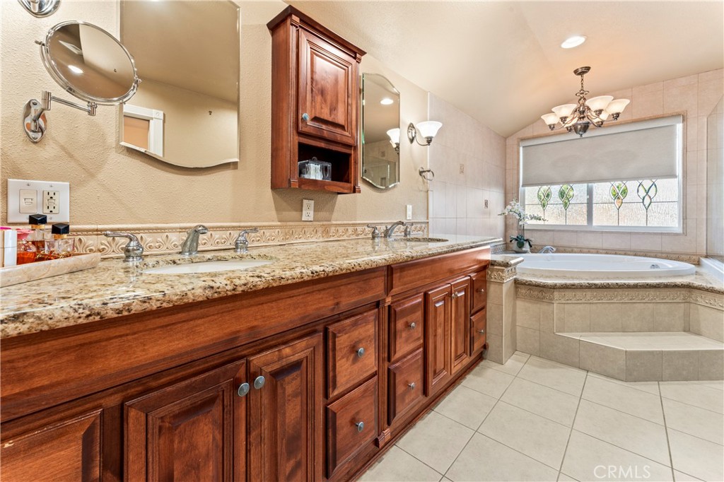 5737 Peridot Avenue Rancho Cucamonga, CA 91701 - Photo 31 of 40 a bathroom with a granite countertop sink a large mirror and a bathtub