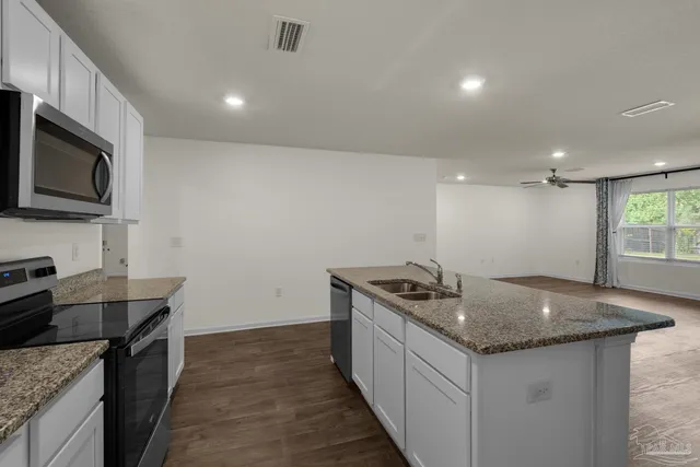 a kitchen with granite countertop stainless steel appliances a sink stove top oven and microwave