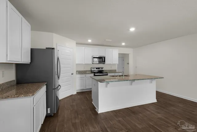 a kitchen with stainless steel appliances granite countertop a stove top oven a refrigerator a sink and dishwasher with wooden floor