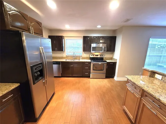 a large kitchen with stainless steel appliances granite countertop a sink stove and refrigerator