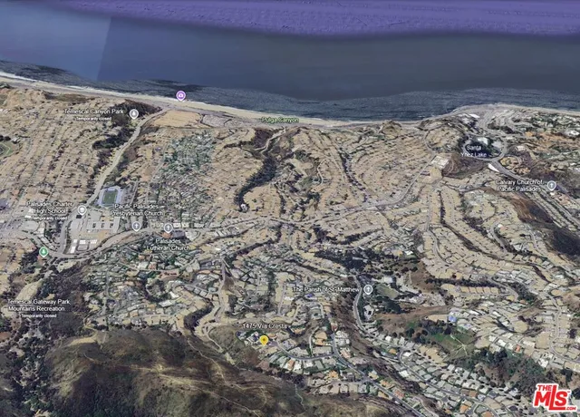a view of a dry field with mountains in the background