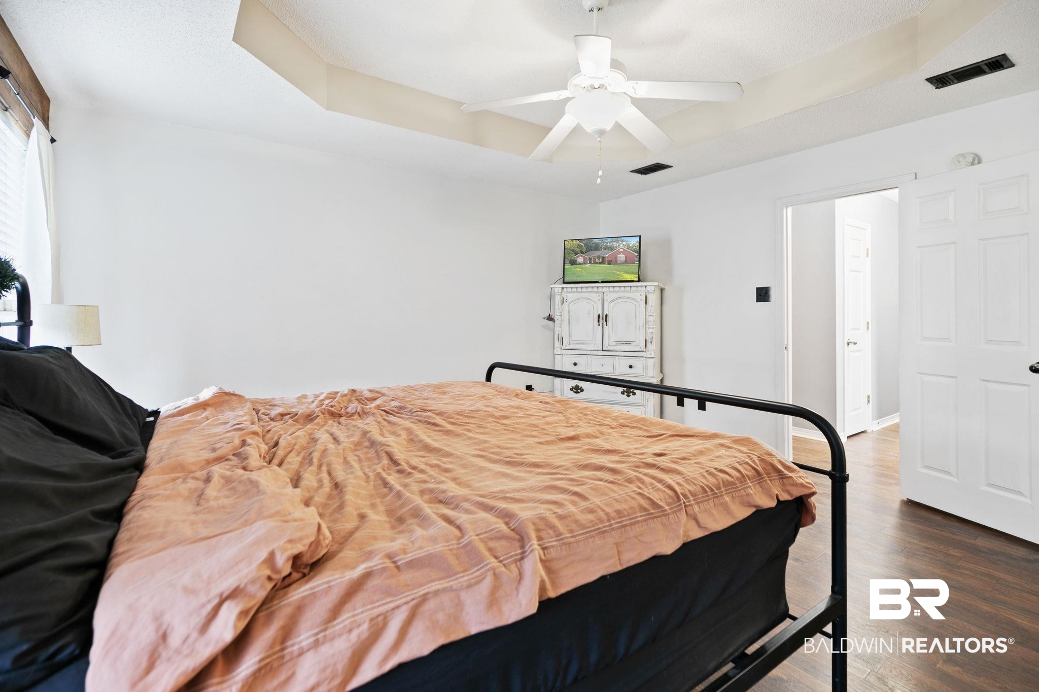 10550 Patrick Avenue Grand Bay, AL 36541 - Photo 24 of 43 Bedroom featuring ceiling fan, a tray ceiling, and wood-type flooring