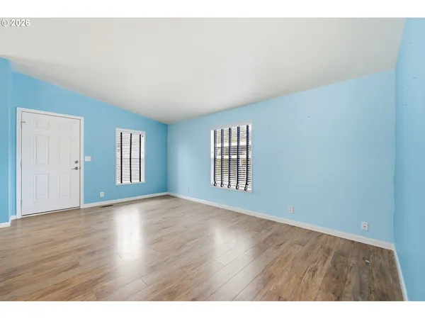 a view of an empty room with wooden floor and windows
