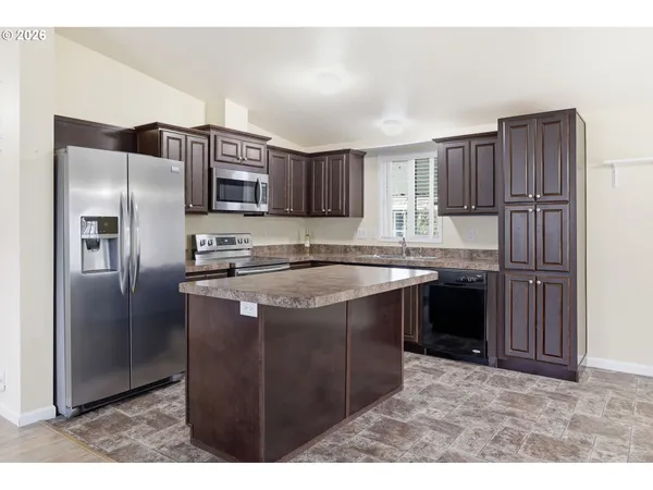 a kitchen with stainless steel appliances granite countertop a refrigerator a sink and a stove