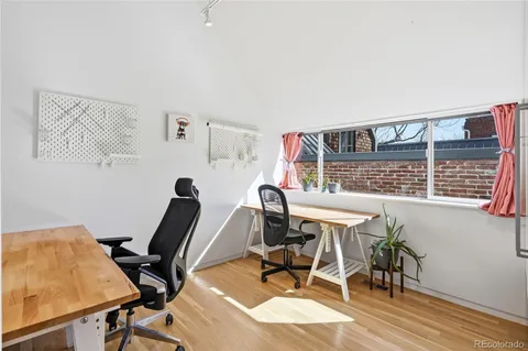 a view of a workspace room with wooden floor and furniture