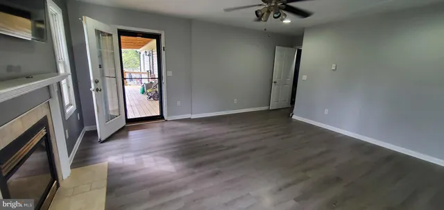 a view of an empty room with a fireplace and a ceiling fan