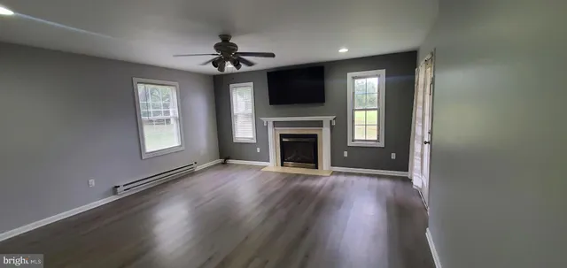 an empty room with windows a fireplace and wooden floor