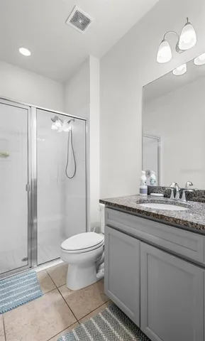 a bathroom with a granite countertop sink a toilet a mirror and shower