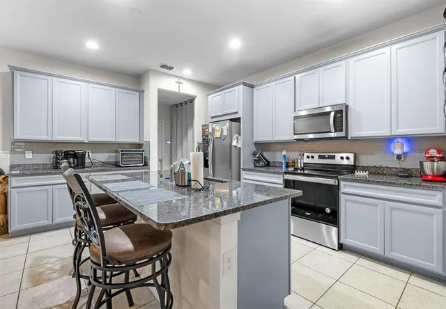 a kitchen with kitchen island granite countertop a stove sink microwave and cabinets