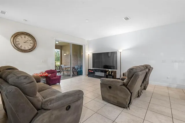 a living room with furniture a clock on wall and a flat screen tv