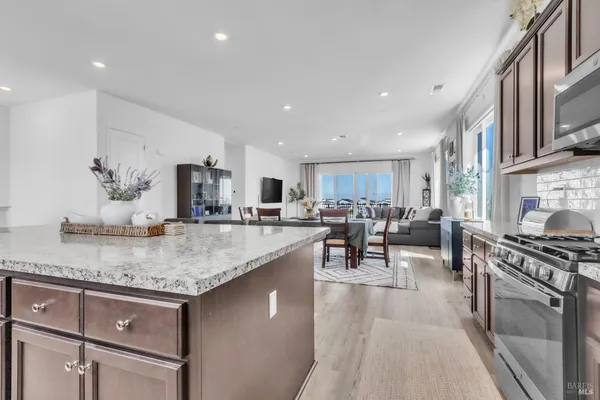 a kitchen with stainless steel appliances granite countertop a stove a sink a oven and a dining table