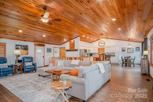 a living room with furniture a rug kitchen view and a large window