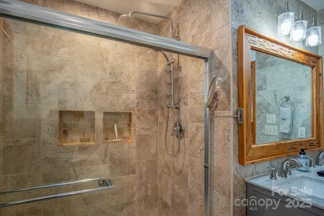 a bathroom with a granite countertop sink a mirror and shower