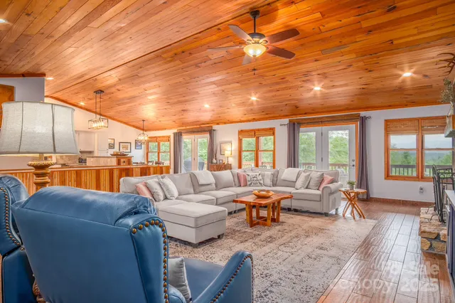 a living room with furniture a large window and wooden floor