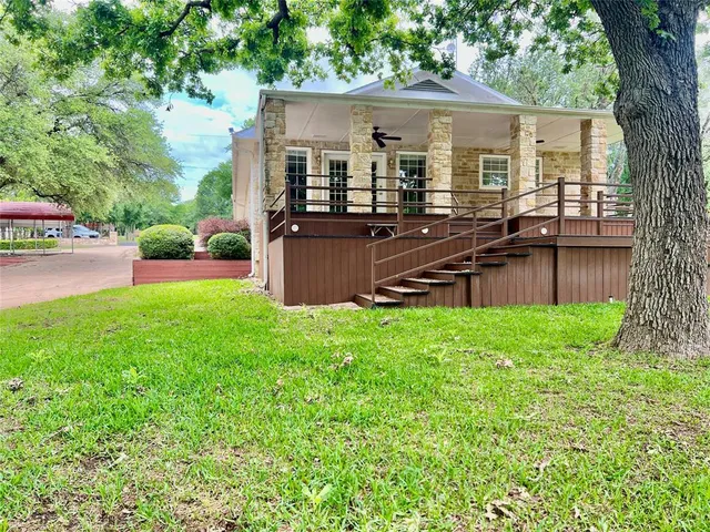 front view of a house with a yard and a wooden deck