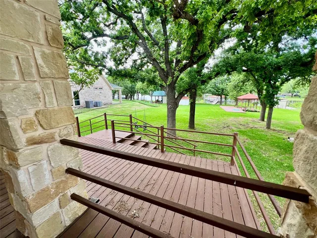 a view of a two chairs in the deck under a large tree