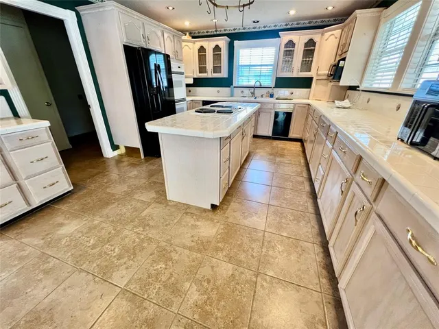 a kitchen with stainless steel appliances a stove a sink a refrigerator a window and a fireplace