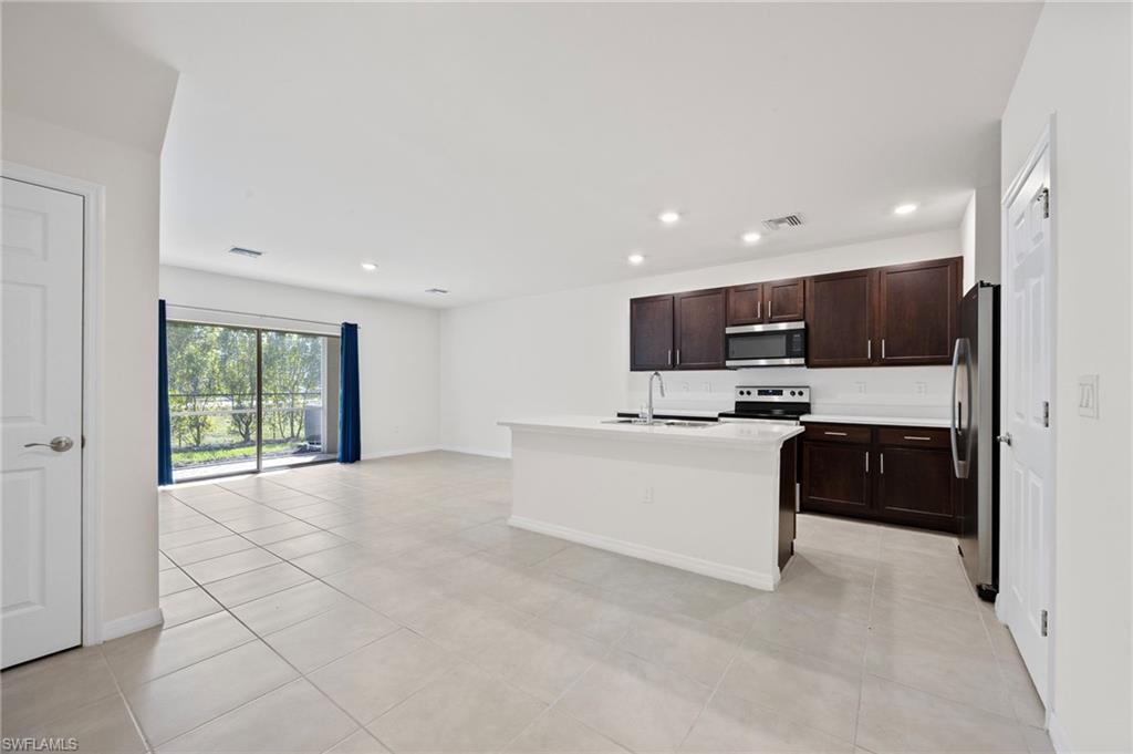 15071 Wildflower Circle Naples, FL 34119 - Photo 32 of 34 a living room with stainless steel appliances kitchen island granite countertop a refrigerator and a stove top oven