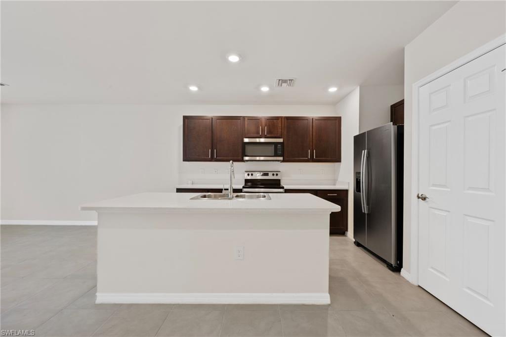 15071 Wildflower Circle Naples, FL 34119 - Photo 3 of 34 a kitchen with stainless steel appliances a refrigerator sink and microwave