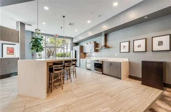 a kitchen with stainless steel appliances granite countertop a stove top oven a sink dishwasher a dining table and chairs with wooden floor