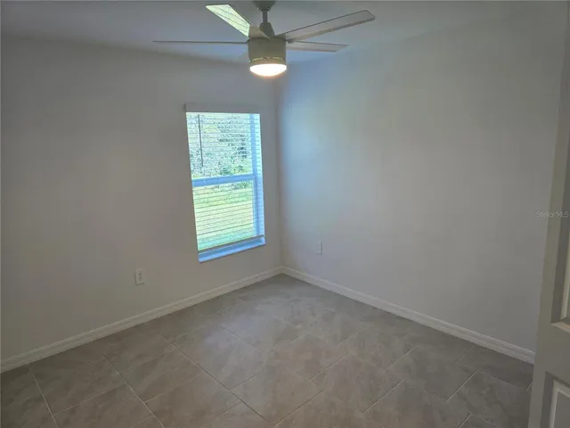 an empty room with windows and fan