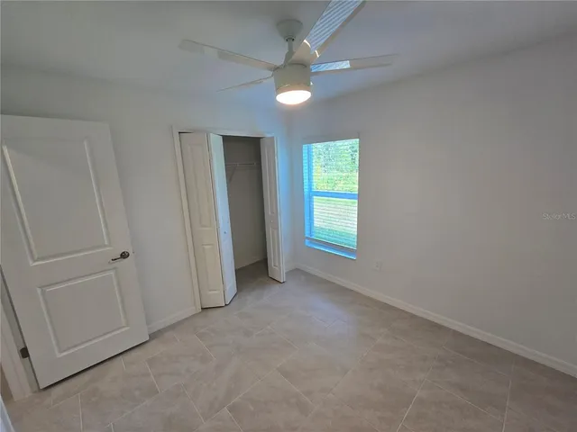 an empty room with windows and fan