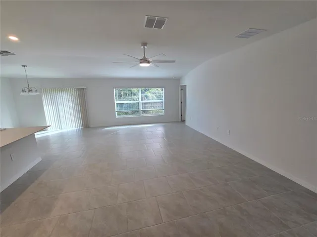 an empty room with windows and chandelier fan