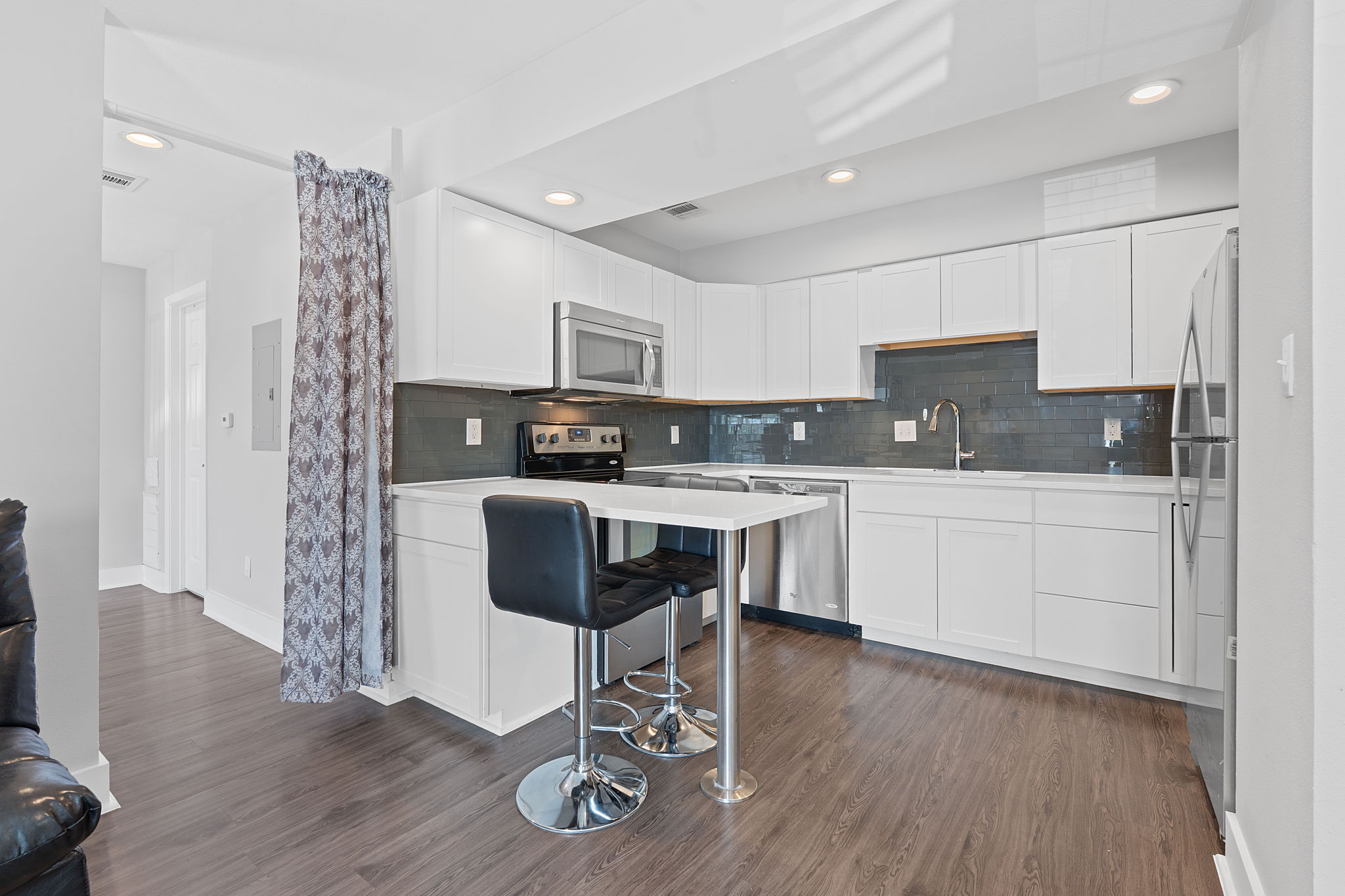 935 La Posada Drive, Unit 254 Austin, TX 78752 - Photo 3 of 18 Kitchen with white cabinets, a kitchen bar, stainless steel appliances, dark wood-style floors, and recessed lighting