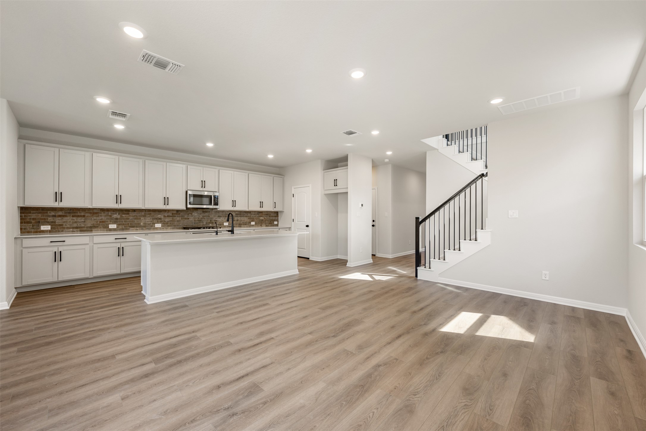 1036 Sienna Bear Road Georgetown, TX 78633 - Photo 6 of 33 a large white kitchen with kitchen island a sink wooden floor stainless steel appliances and cabinets