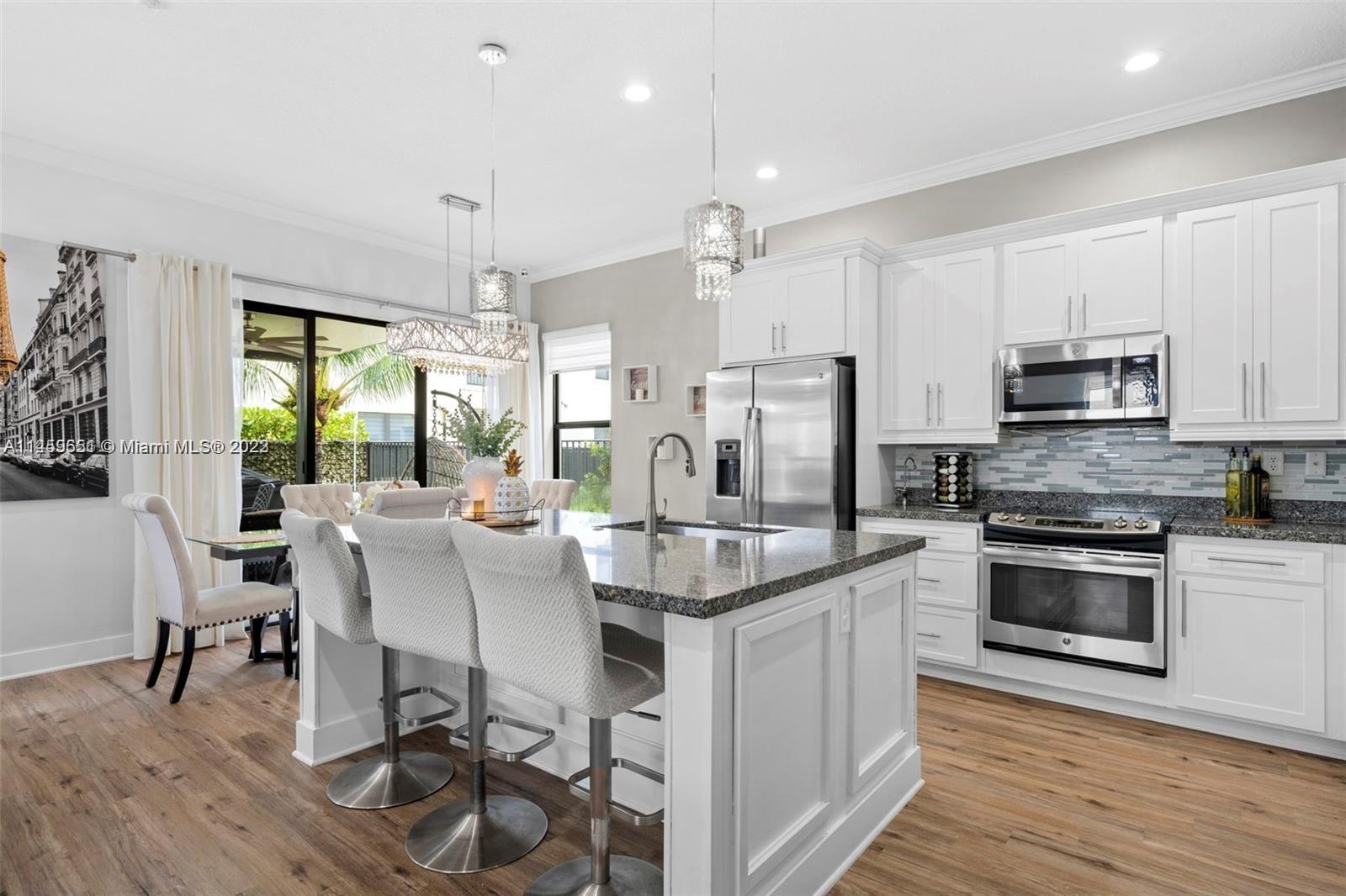 Hialeah Hialeah, FL 33018 - Photo 8 of 54 a kitchen with stainless steel appliances granite countertop a stove top oven a sink dishwasher a dining table and chairs with wooden floor