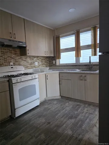 a kitchen with granite countertop wooden cabinets appliances a sink and a window