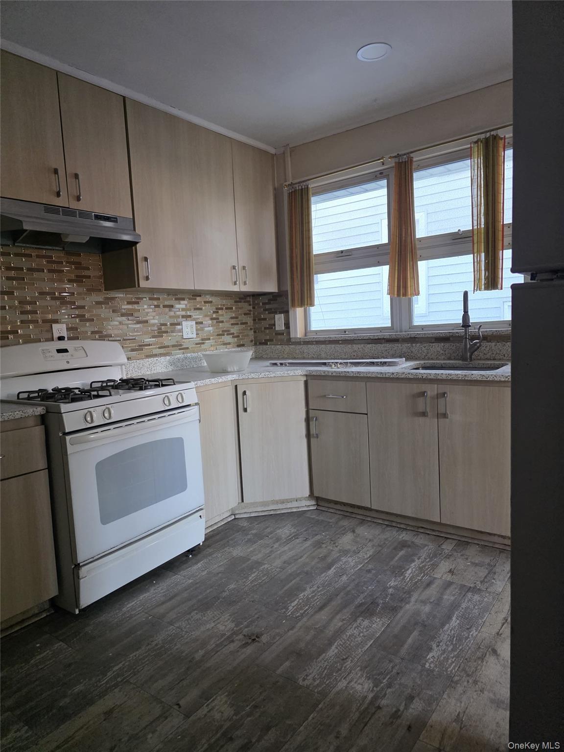 a kitchen with granite countertop wooden cabinets appliances a sink and a window