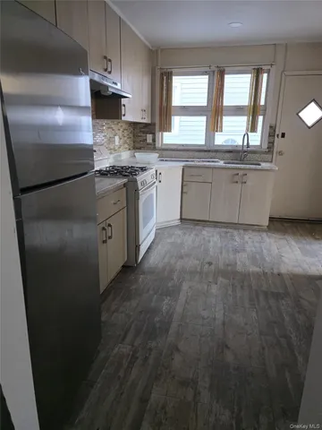 a kitchen with stainless steel appliances granite countertop a refrigerator a sink a stove and white cabinets