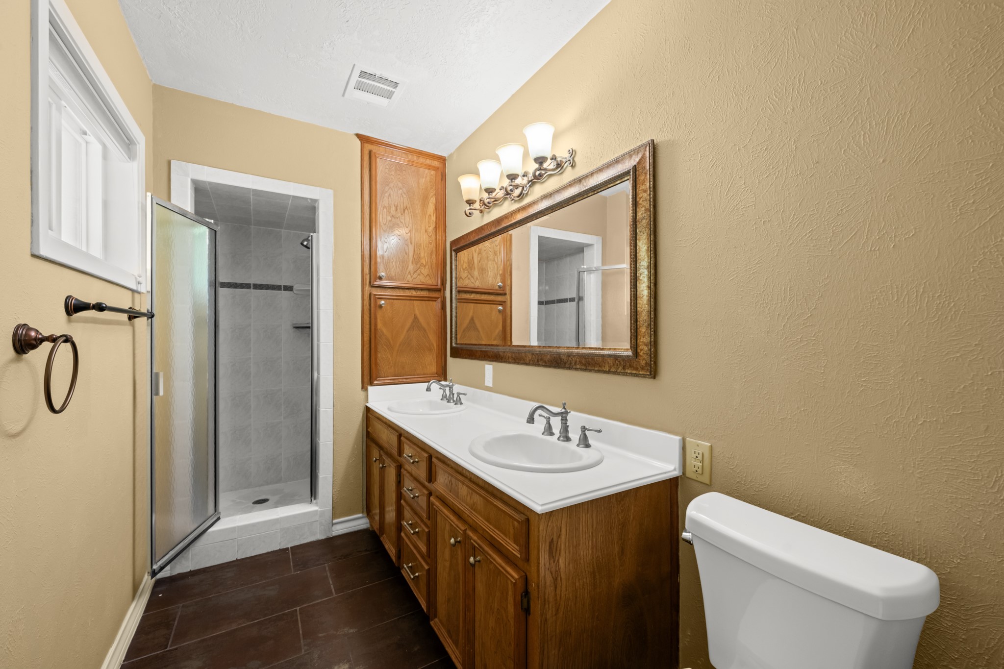616 Cannan Drive Angleton, TX 77515 - Photo 21 of 49 The private primary bath features an oversized vanity with ample storage, a large framed mirror, and updated lighting. A spacious walk-in shower and warm wood cabinetry create a comfortable, functional retreat designed for everyday convenience.