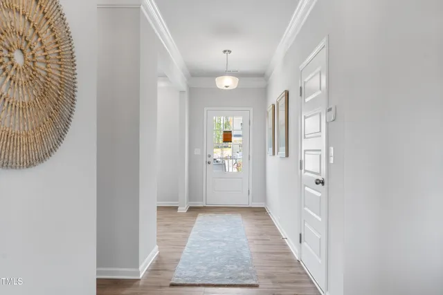 a view of a hallway with wooden floor and a bathroom