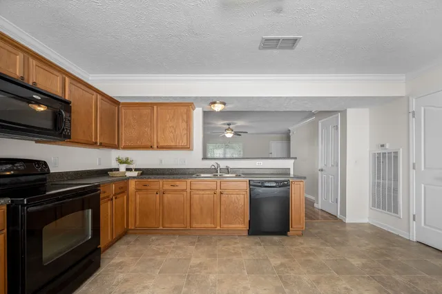 a kitchen with stainless steel appliances granite countertop a stove top oven a sink dishwasher and a refrigerator