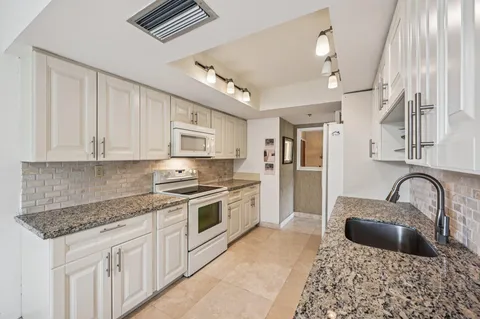 a kitchen with granite countertop a sink and refrigerator