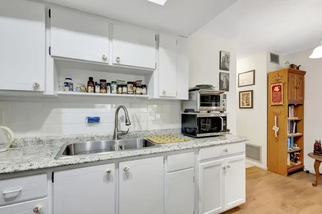 a kitchen with stainless steel appliances granite countertop a sink and a white cabinets