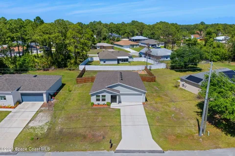 an aerial view of a house with swimming pool and trees