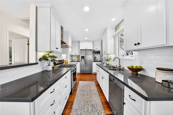 a kitchen with kitchen island granite countertop a sink a counter top space stainless steel appliances and cabinets