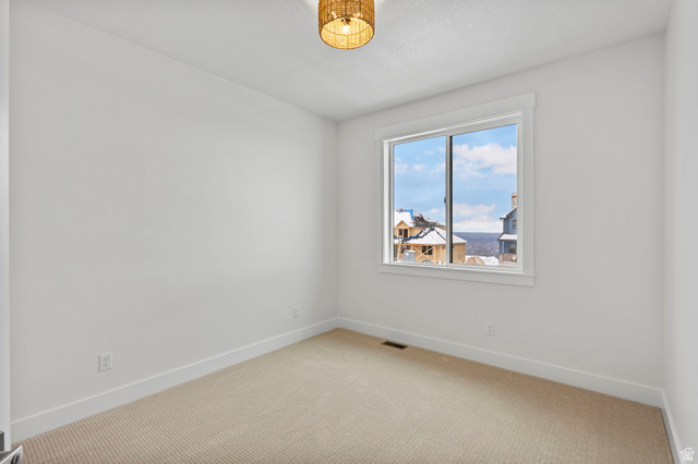728 East Mountain Road North Ogden, UT 84414 - Photo 28 of 28 Bright room featuring a large window, neutral carpeting, white trim, and a woven ceiling light fixture