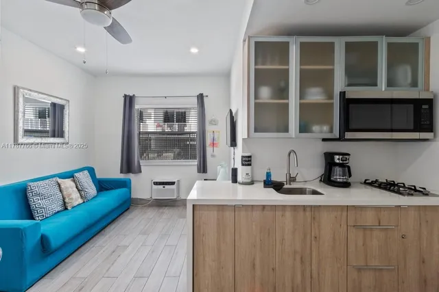 a living room with stainless steel appliances kitchen island granite countertop a couch and a wooden floor