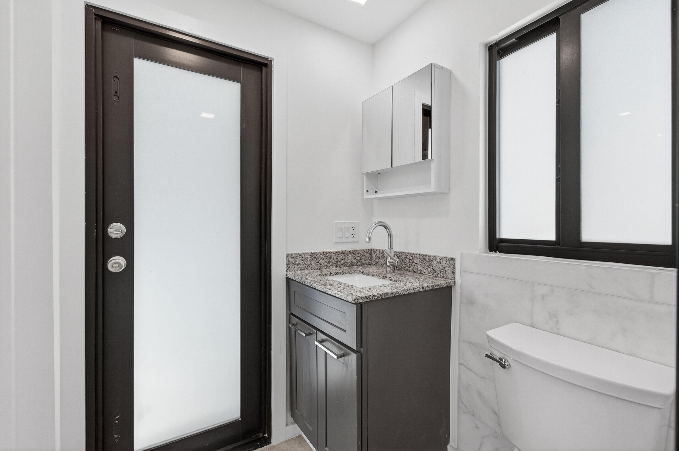 515 Northwest 1st Street, Unit 1 Delray Beach, FL 33444 - Photo 35 of 35 a bathroom with a granite countertop toilet sink and mirror