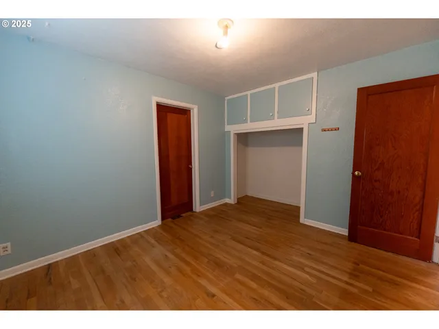 a view of an empty room with wooden floor and closet