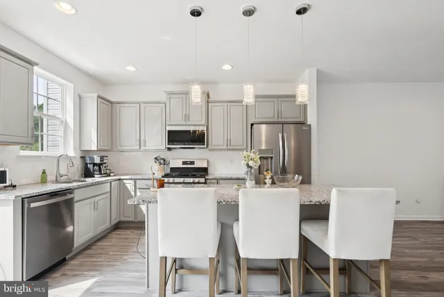 a kitchen with stainless steel appliances granite countertop a stove top oven a sink dishwasher a dining table and chairs with wooden floor