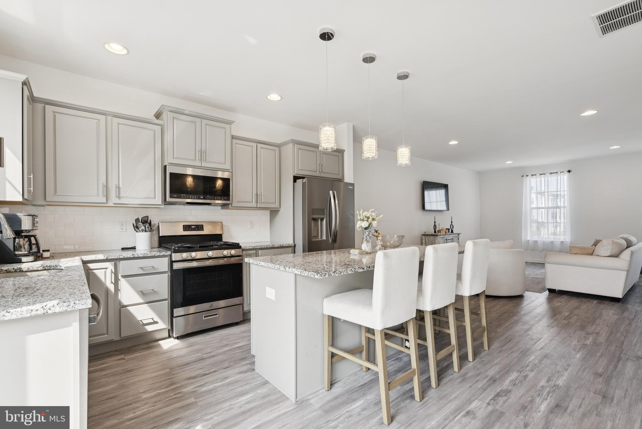 94 Aviary Road Thorofare, NJ 08086 - Photo 12 of 24 a kitchen with stainless steel appliances granite countertop a stove top oven a sink dishwasher a dining table and chairs with wooden floor