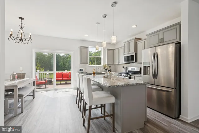 a kitchen with stainless steel appliances a table chairs refrigerator and cabinets