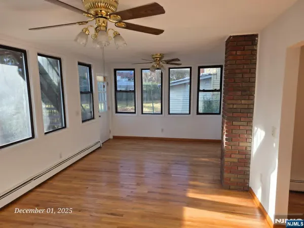 a view of an empty room with a window and wooden floor