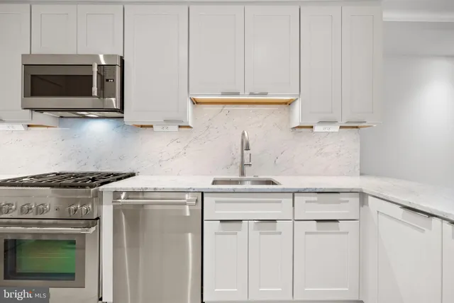 a kitchen with granite countertop white cabinets and stainless steel appliances